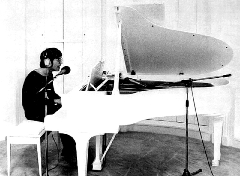 John Lennon playing a piano in black outfit