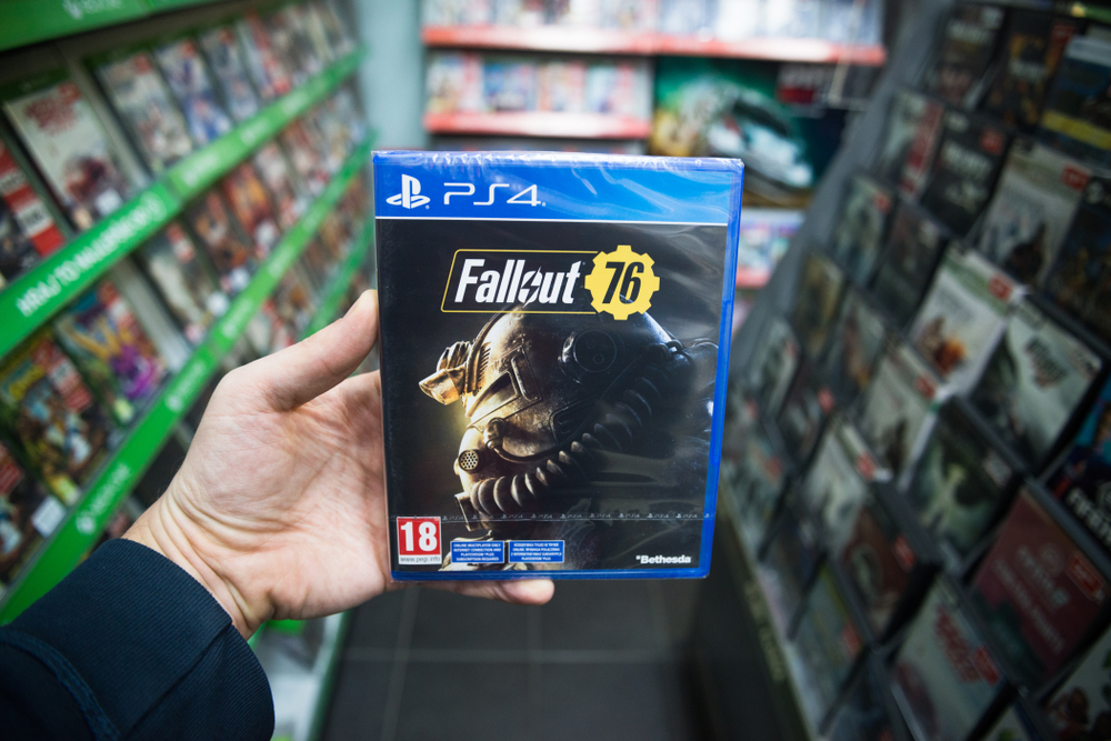 Man holding Fallout 76 videogame on Sony Play station 4 console in store