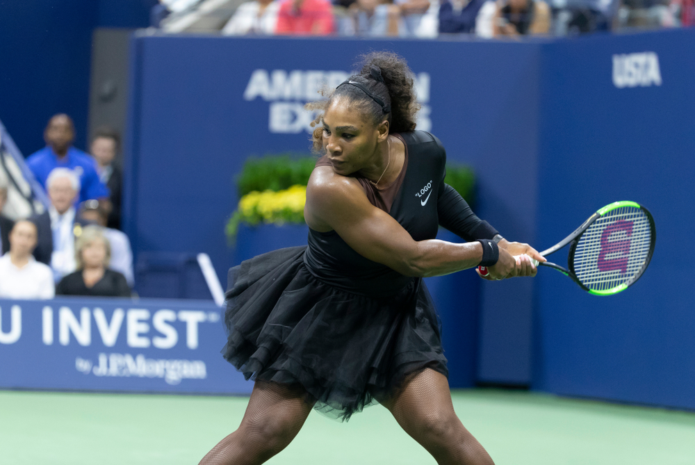 Serena Williams of USA in black outfit returns ball during US Open 2018