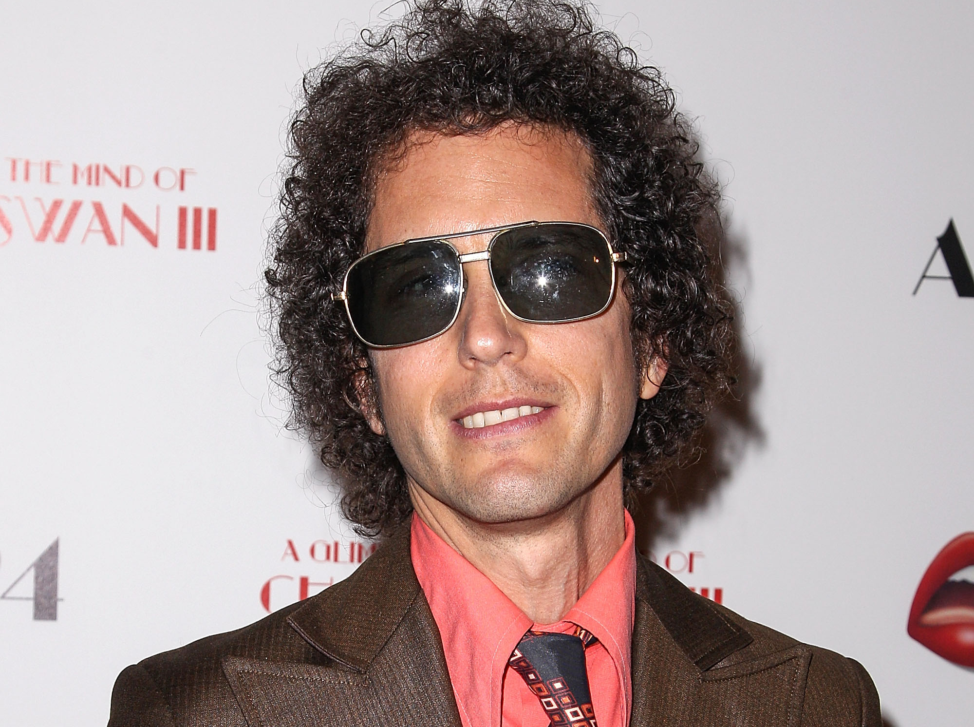 Composer Liam Hayes at a premiere in brown suit and pink shirt