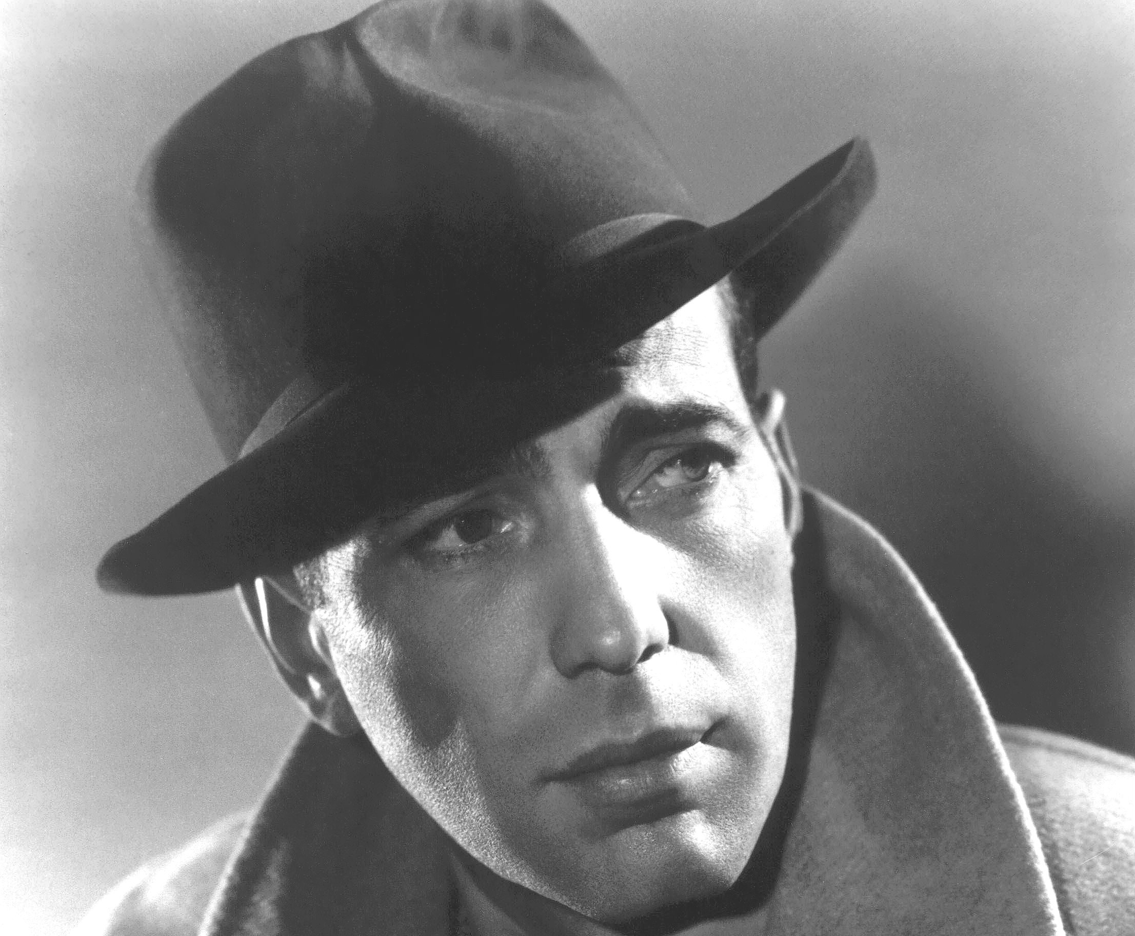 Grayscale Portrait Photo of Humphrey Bogart in a gray cot and hat