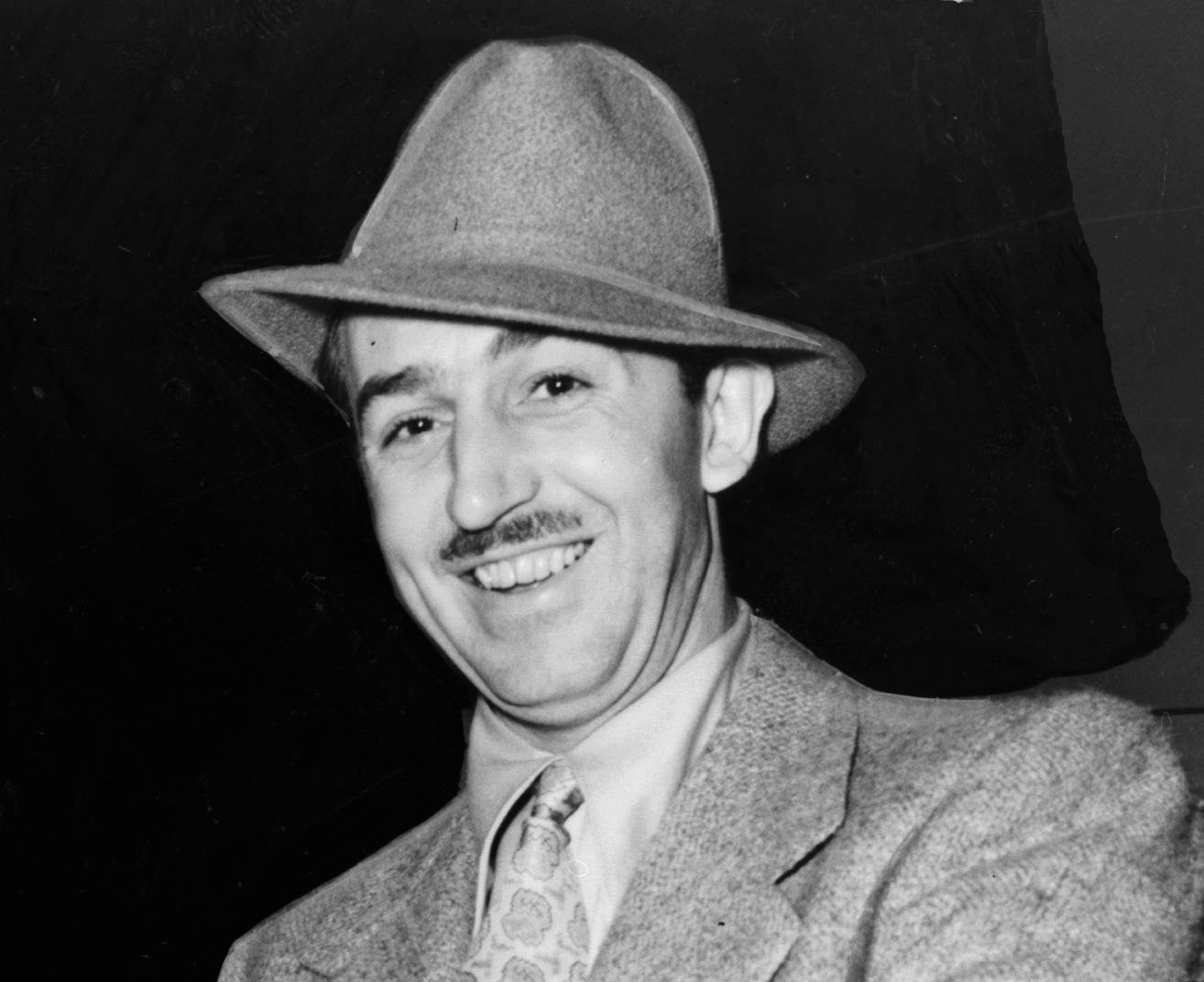 Grayscale Portrait Photo of Walt Disney in a gray suit and hat