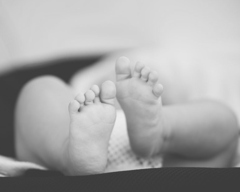 shallow focus photography of baby wearing white diaper lying