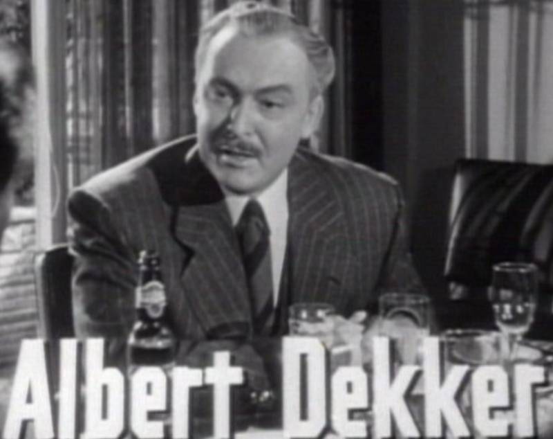 Albert Dekker in suit sitting at a desk