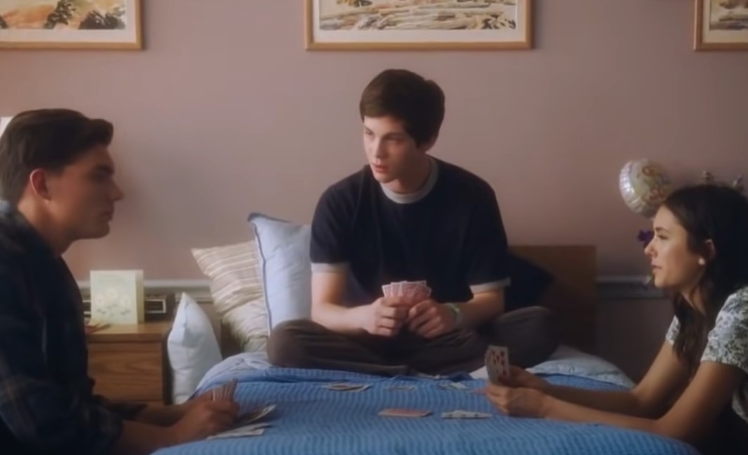 two boys and a girl playing cards on the bed