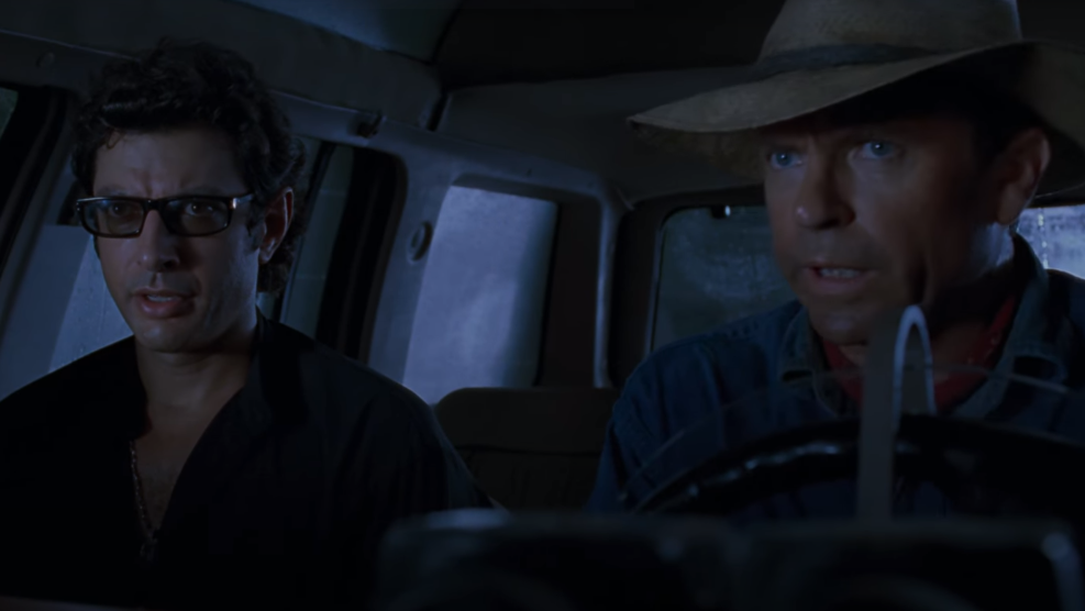 image of two man driving in a car from film Jurassic Park