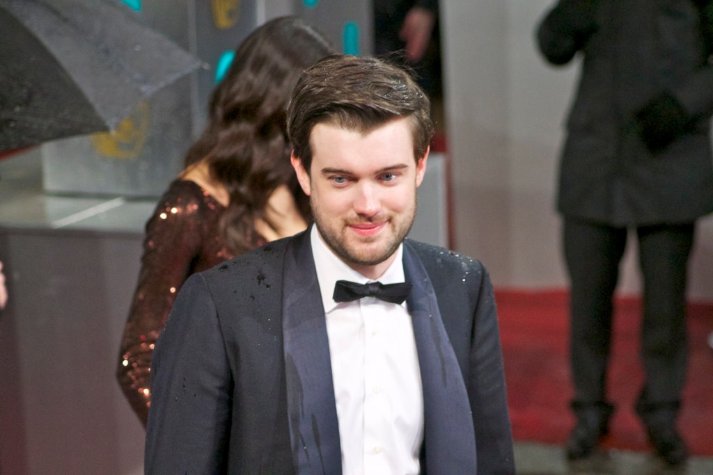 Portrait Photo of Jack Whitehall in a dark suit smiling and facing the camera