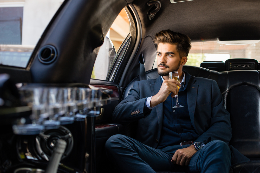 Business man in limousine with glass of champagne