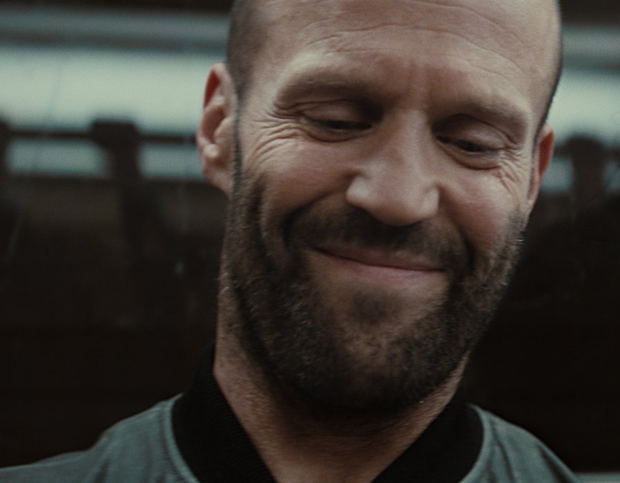 Portrait Photo of the Actor Jason Statham, smiling, looking downwards.