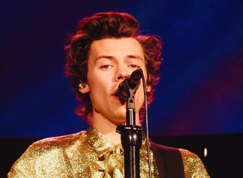 Portrait Photo of Harry Styles wearing a golden outfit while performing on stage