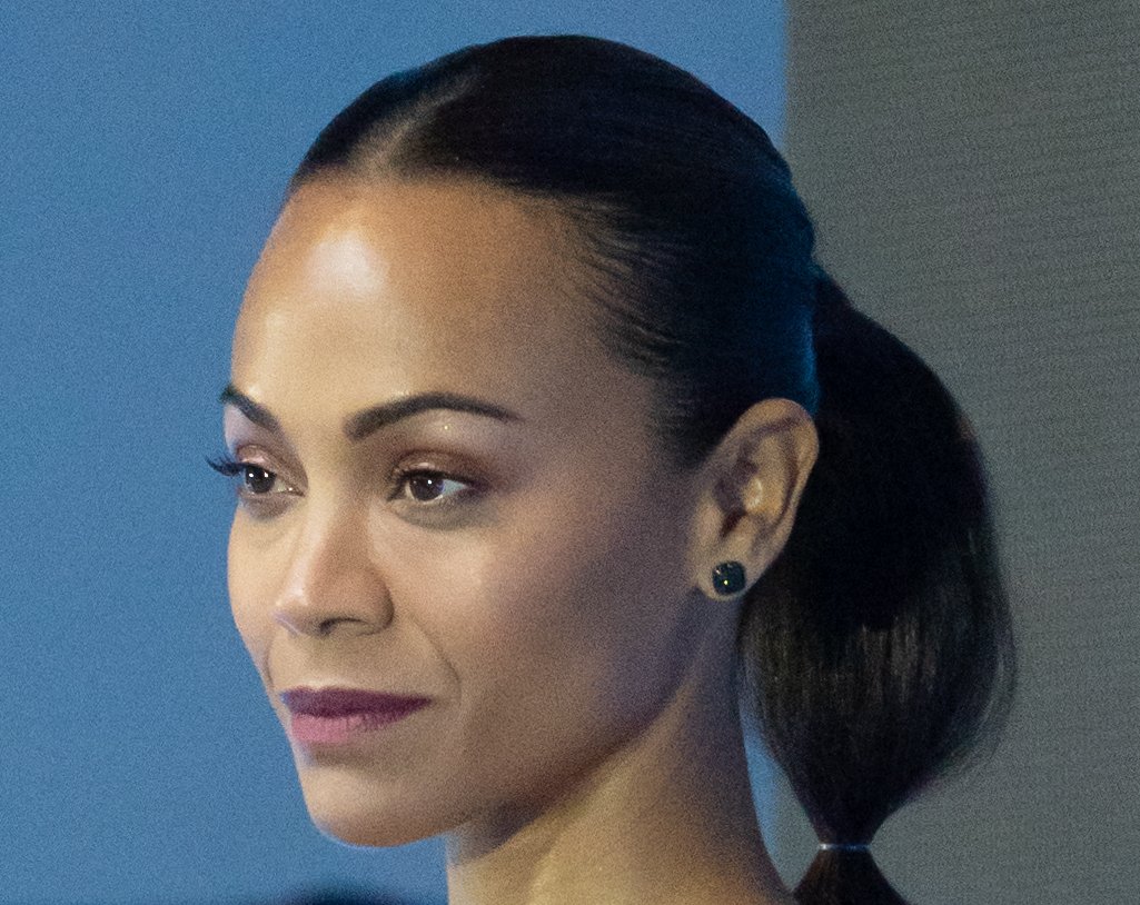 Portrait Photo of Zoe Saldana, looking to the left, smiling.