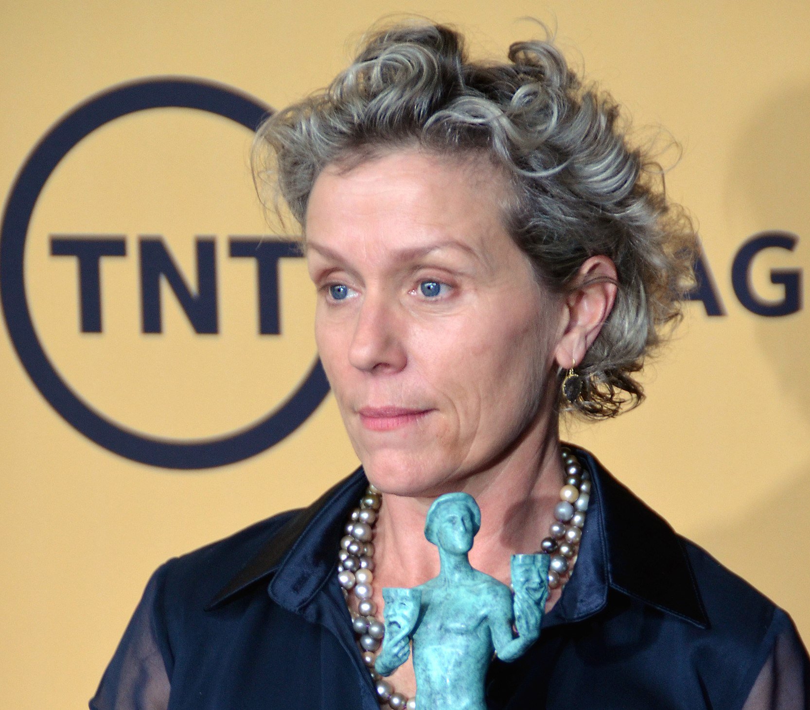 Portrait Photo of Actress Frances McDormand holding award statue.