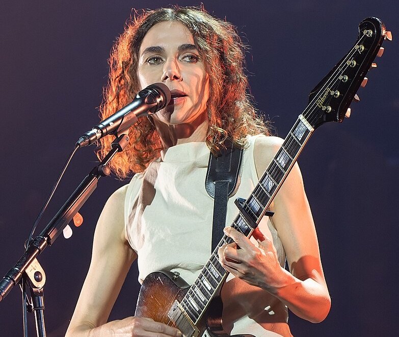 Portrait Photo of PJ Harvey in a white dress performing on stage