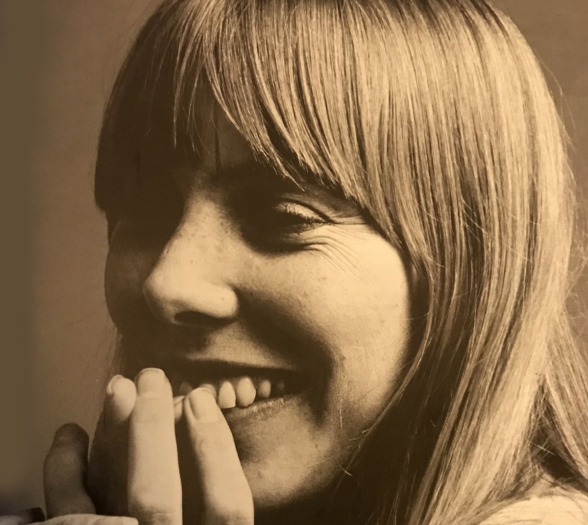 Grayscale Portrait Photo of Joni Mitchell smiling with her eyes closed.