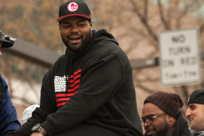 Portrait Photo of Michael Oher in a dark hoody and hat smiling