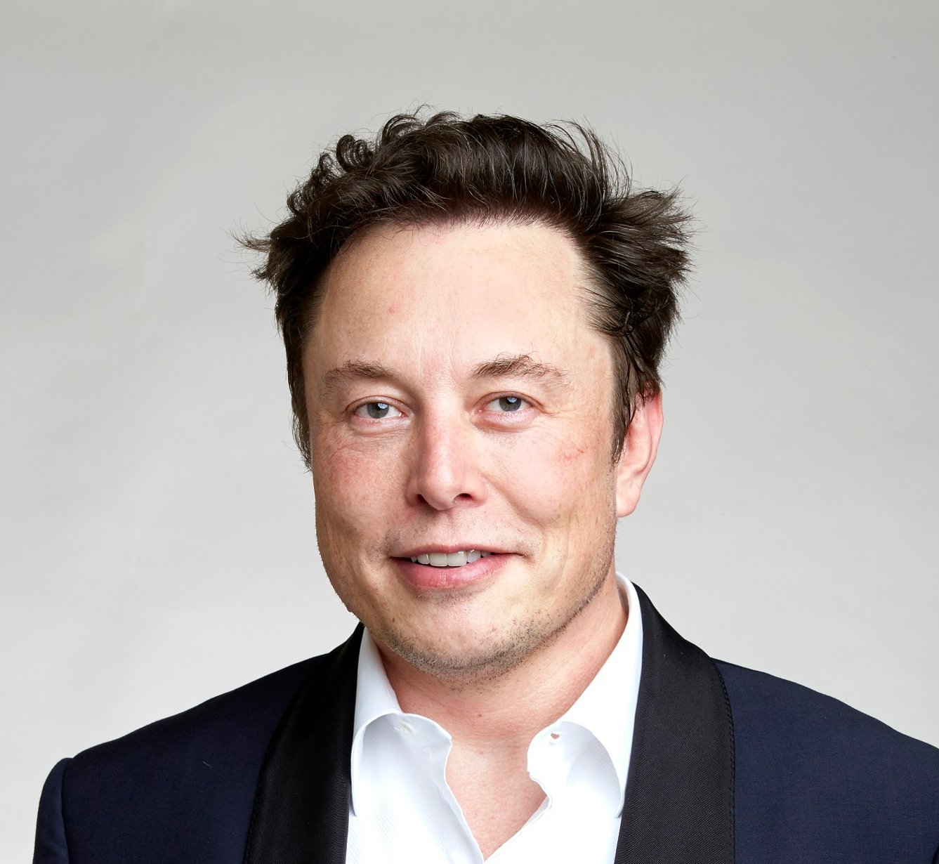 Portrait Photo of Elon Musk in dark suit, facing the camera.