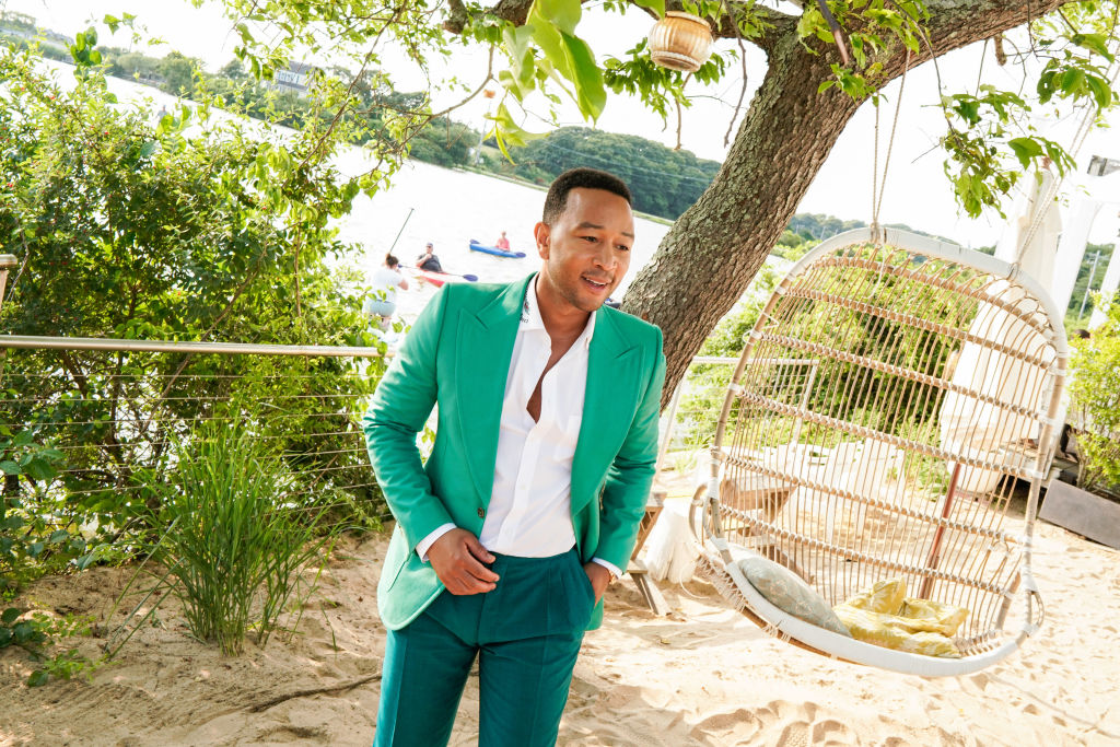 John Legend in green suit close to a beach