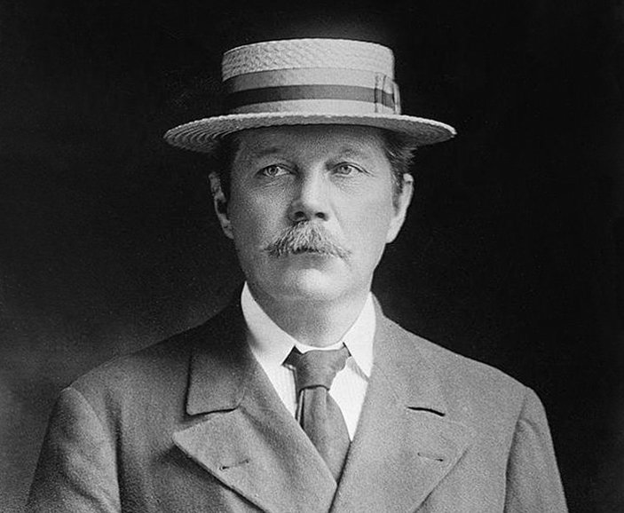 Grayscale Portrait Photo of Arthur Conan Doyle in a gray suit and hat