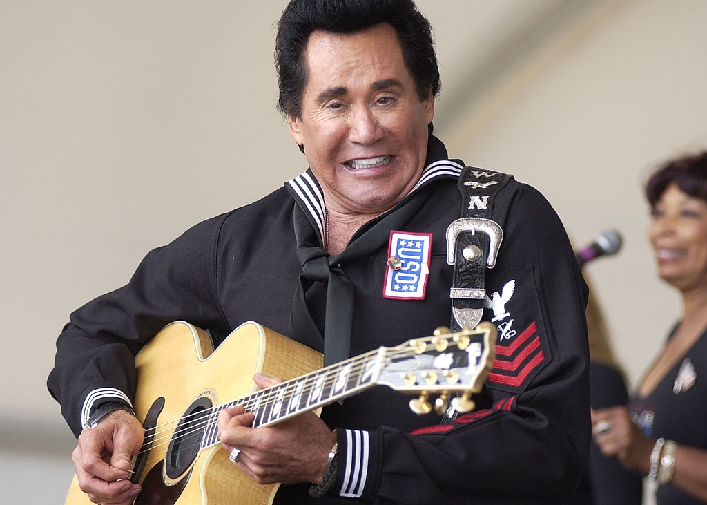 Musician/Actor Wayne Newton strums the guitar during his USO show