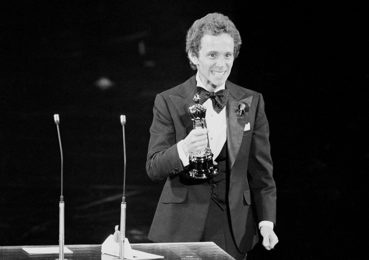 Joel Gray grimaces as he holds up his