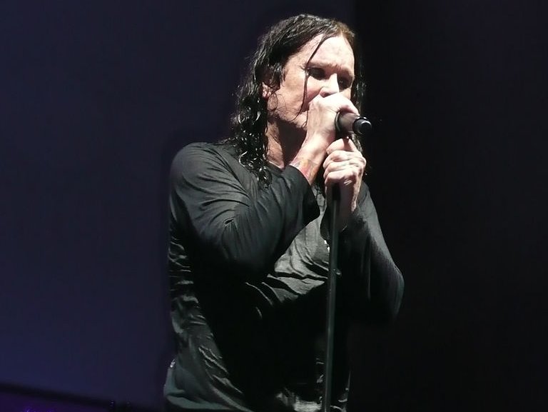 Portrait Photo of Ozzy Osbourne in dark outfit performing on stage