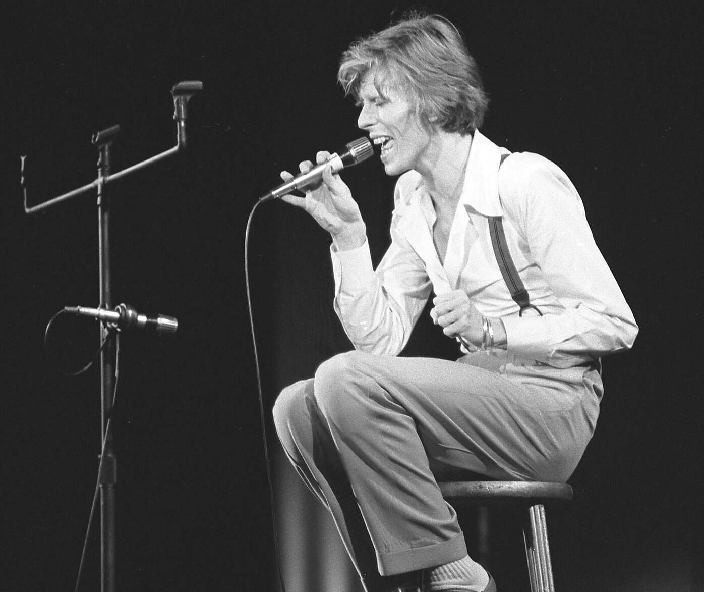 Portrait Photo of David Bowie, seated on stool during performance