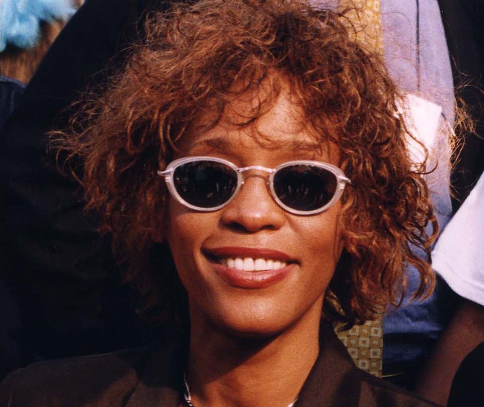 Portrait Photo of Whitney Houston in dark outfit and sunglasses