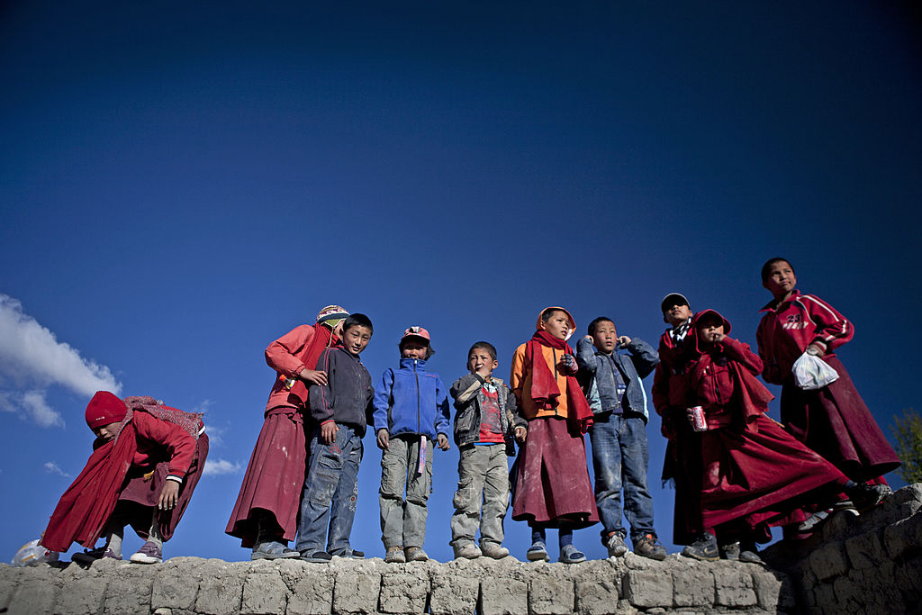 Loba children and monks gather atop a mud wall to watch events during the Tiji Festival.
