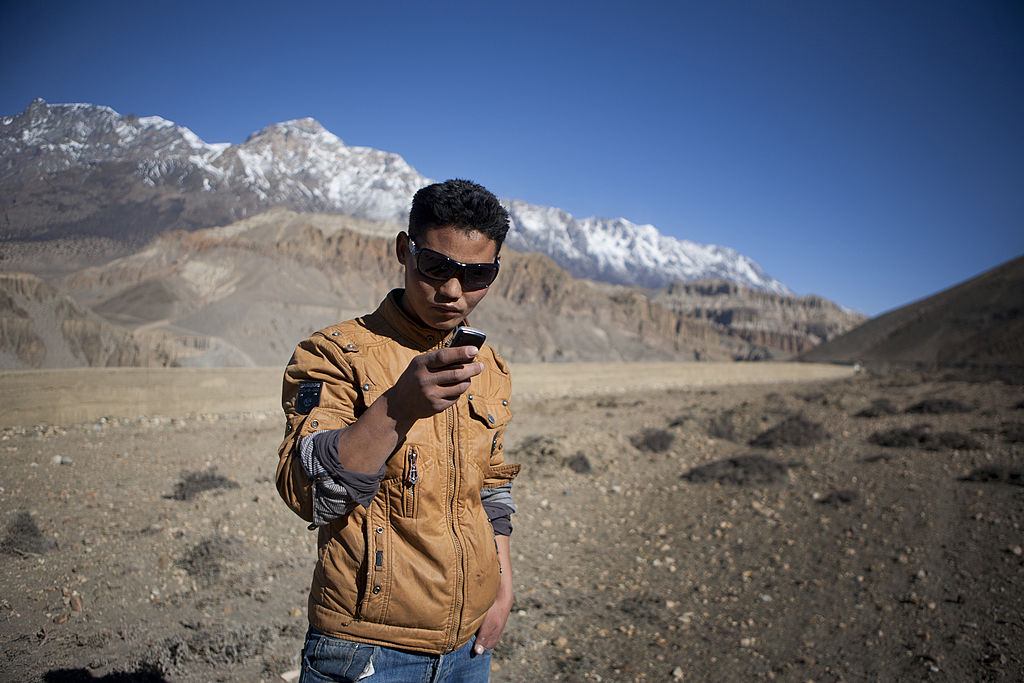 Man of kingdom of Mustang in modern clothes holding cell phone