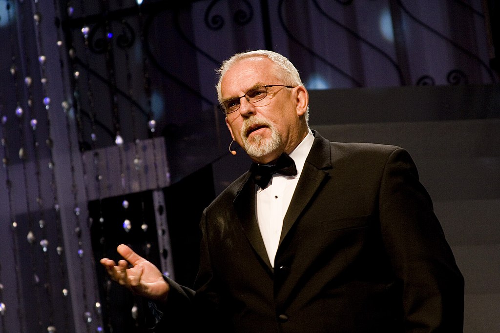 John Ratzenberger in a black suit