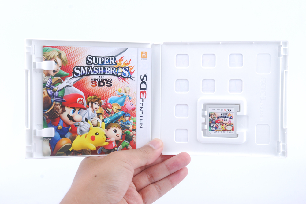 Man holding super smash bros Video Game on Nintendo 3DS console on white background.