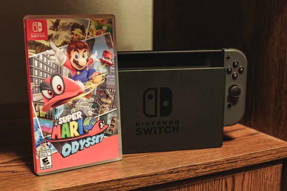 The video game Super Mario Odyssey next to a Nintendo Switch, on a shelf.