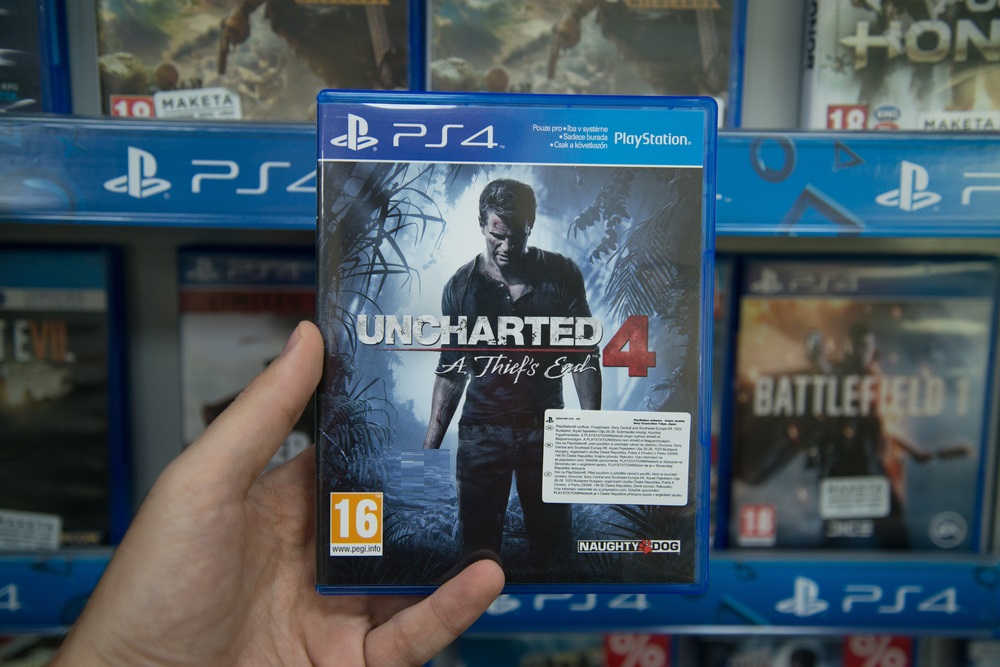Man holding Uncharted 4 A thief's end videogame on Sony Playstation 4 console in store