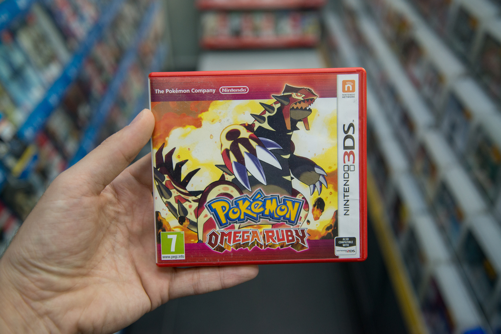 Man holding Pokemon omega ruby videogame on Nintendo 3DS console in store