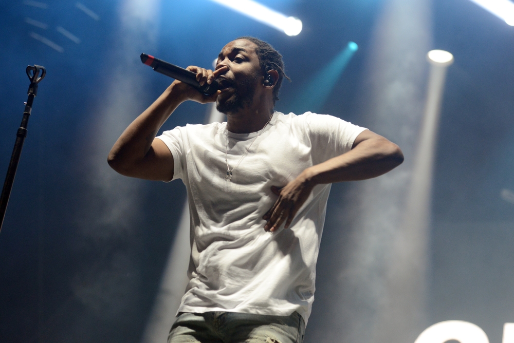 Kendrick Lamar performing onstage in a white top