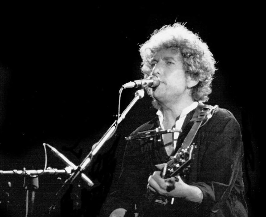 Grayscale Photo of Bob Dylan performing on stage in Barcelona