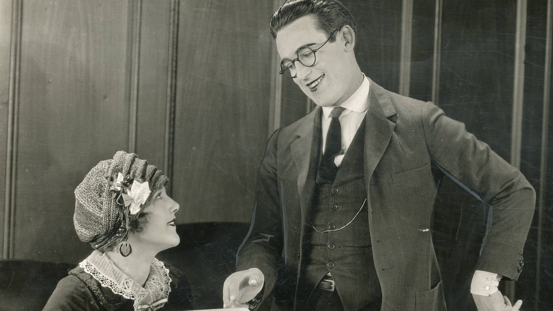 Photo of Harold Lloyd smiling and Mildred Davis holding a paper and looking at him - Still from the American comedy film Safety Last! (1923).