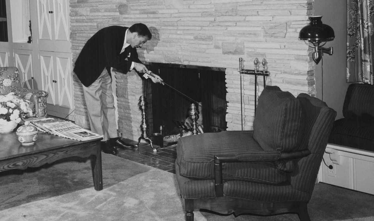 American singer and actor Frank Sinatra (1915-1998) stoking the fireplace in the living room of his home, United States, circa 1950. 