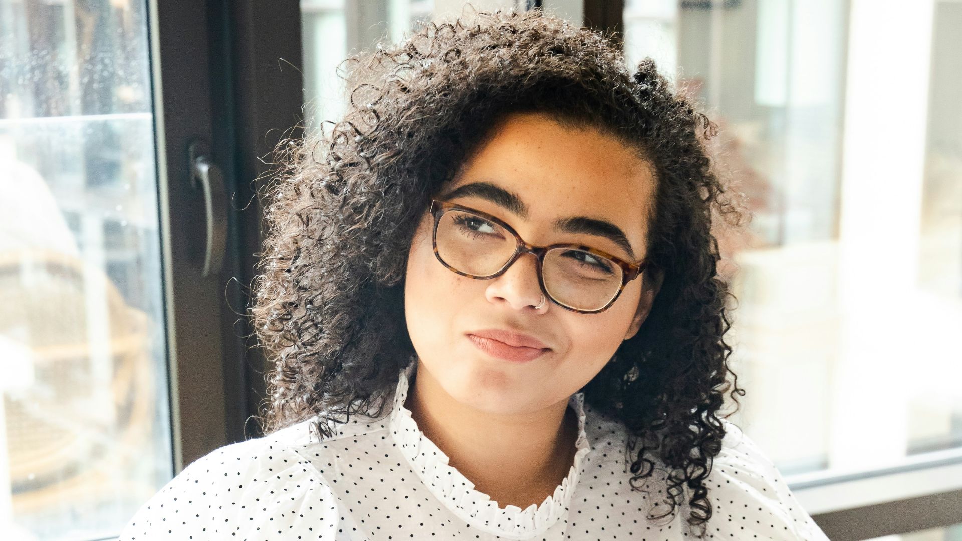 woman in white and black polka dot shirt holding blue and white book