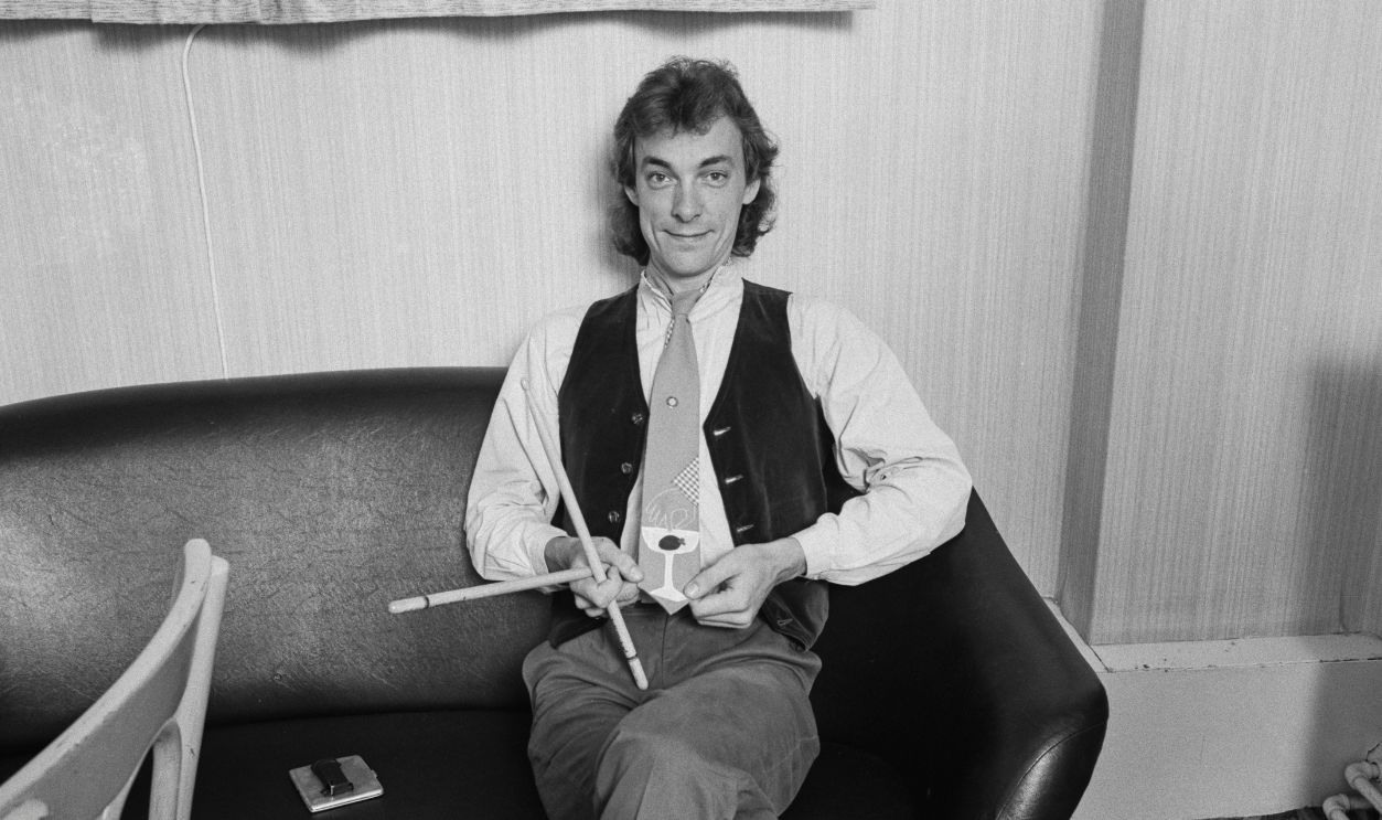 Gettyimages - 1199870753, Neil Peart Backstage Drummer and lyricist Neil Peart (1952 - 2020) of Canadian progressive rock group, Rush, showing off a novelty tie, backstage, 1980. 