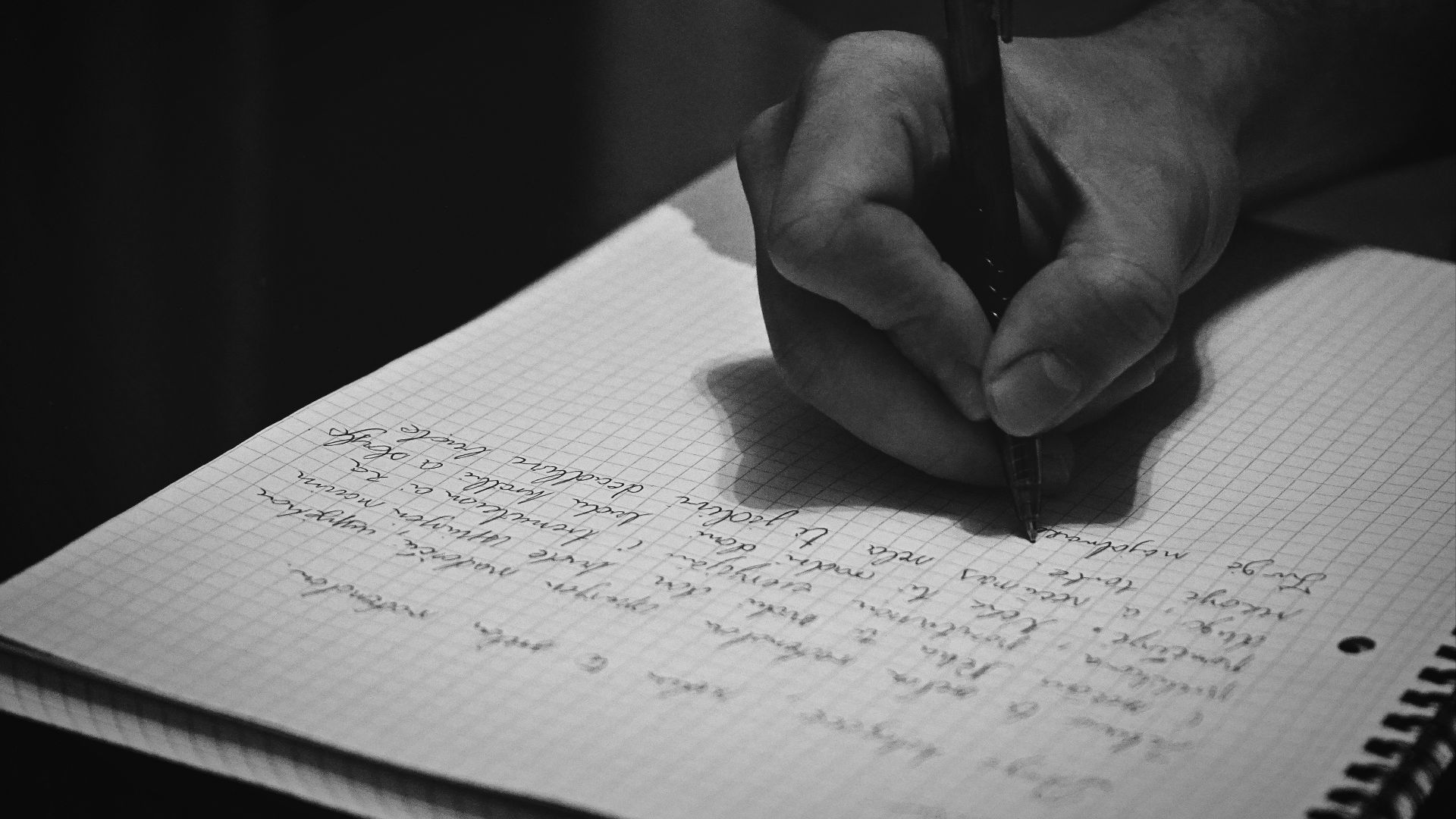 A person writing on a notebook with a pen