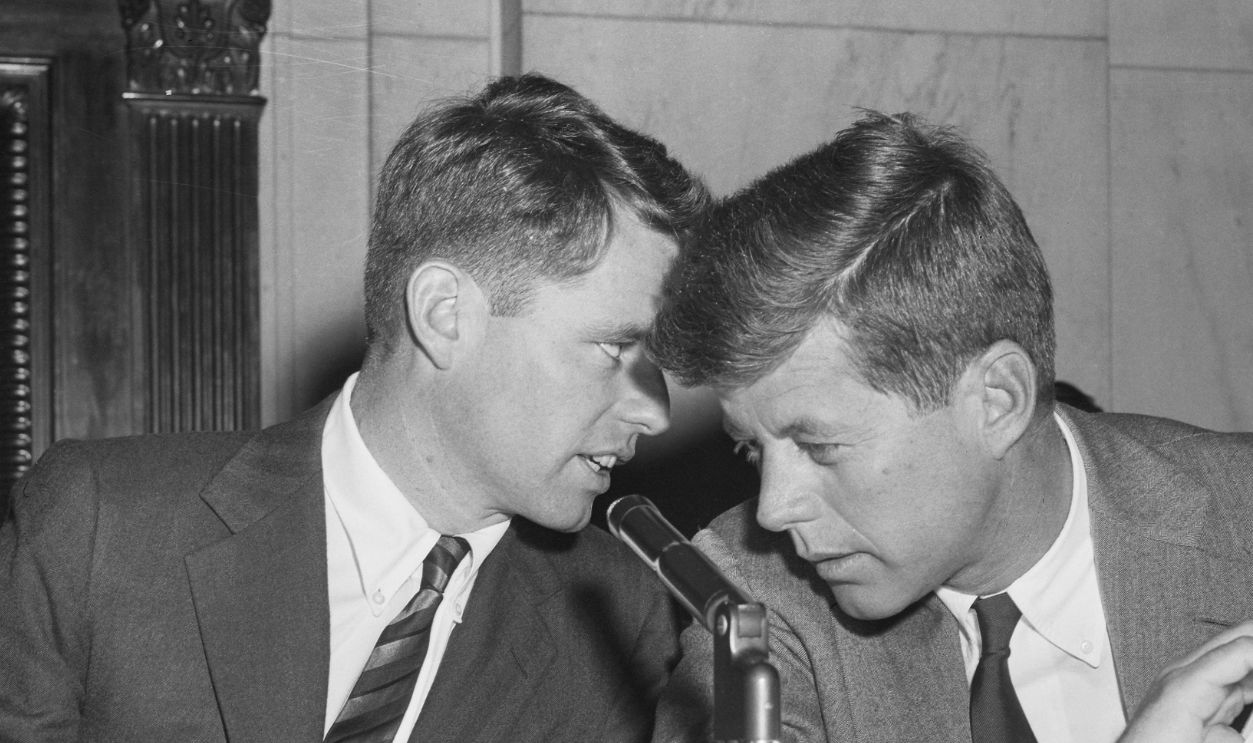 Robert F. Kennedy (left), counsel of the Senate Committee on Racketeering in Labor and Industry, and his brother John F. Kennedy (D-Massachusetts), a member of the committee, confer at the hearing in Washington yesterday which heard testimony about the International Brotherhood of Teamsters. The Senate investigators heard how $30,000 in funds belonging to a Spokane, Washington, local of the Teamsters had been lent to a friend of the son of Dave Beck, the Union's President, to finance a Seattle tavern.
