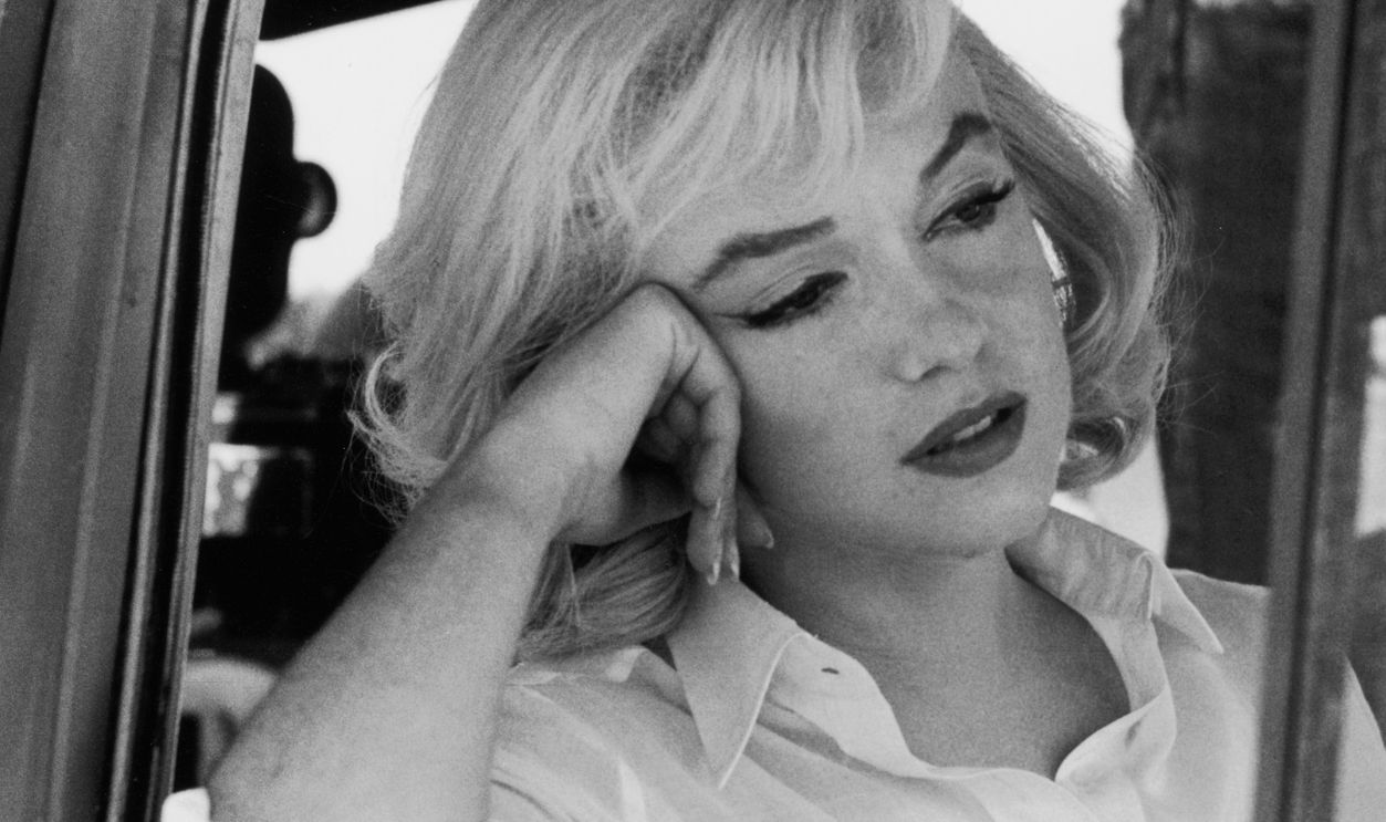American actress Marilyn Monroe (1926 - 1962) (born Norma Jean Mortensen) leans out of the open window frame of a car on the set of 'The Misfits,' directed by John Huston, Nevada, 1960.