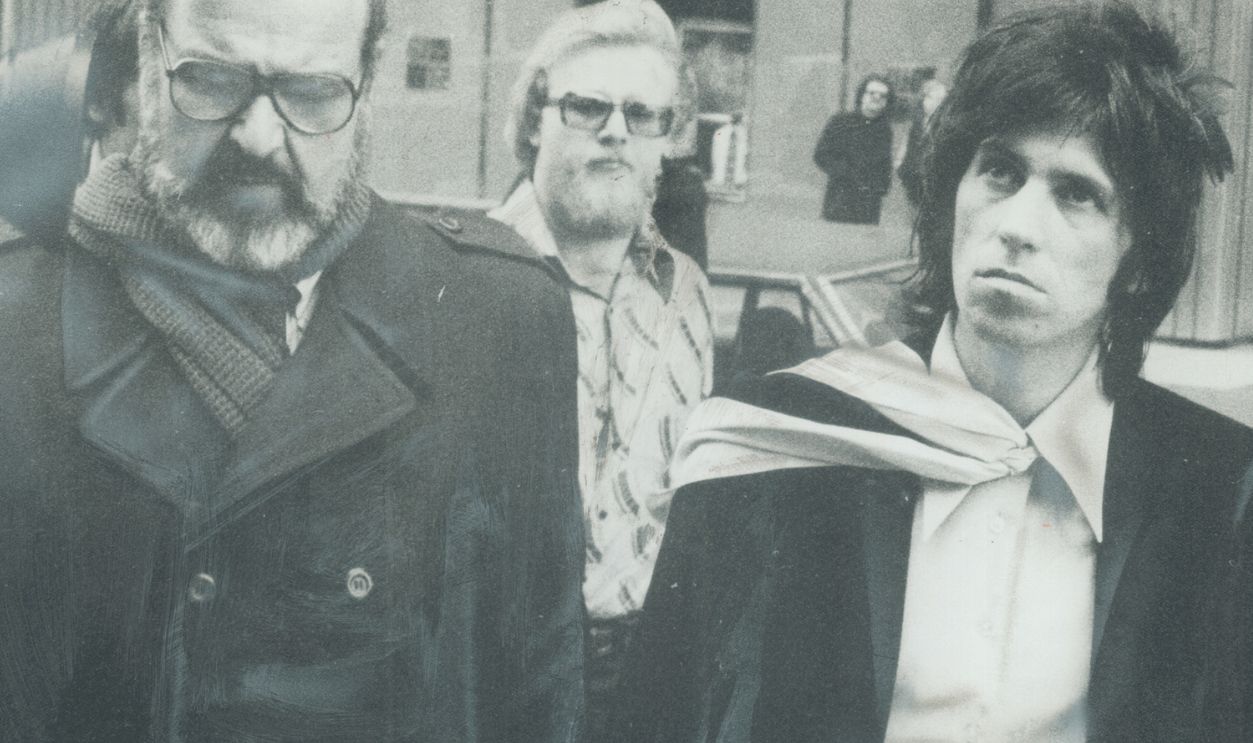 Accompanied by his press agent; Paul Wasserman (left); and with body guard in the background; Rolling Stones guitarist Keith Richard yesterday went to old City Hall