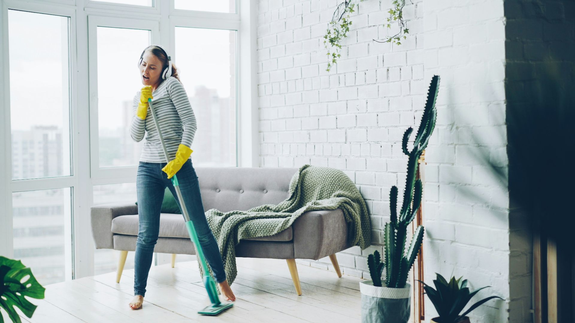 Woman with headphones cleaning and dancing