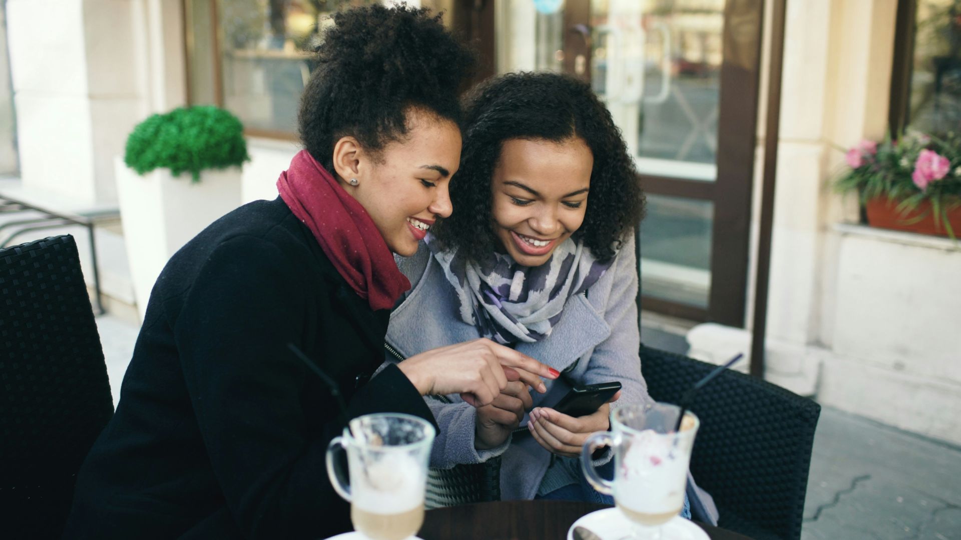 Two women looking at a smartphone together at cafe.