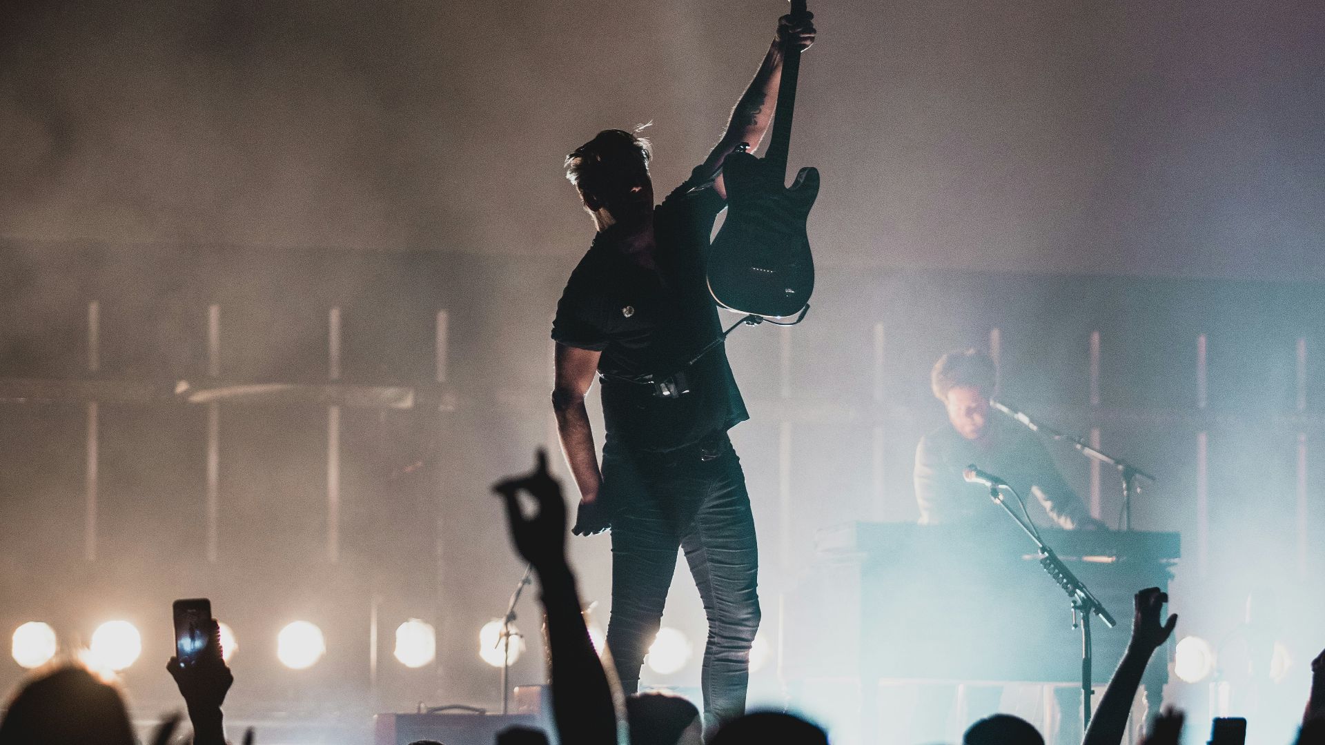 man in black shirt and black pants singing on stage