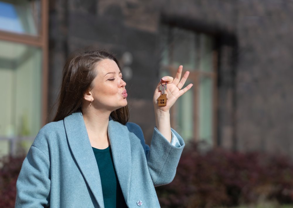 Portrait Photo of Happy woman holding key keychain of home