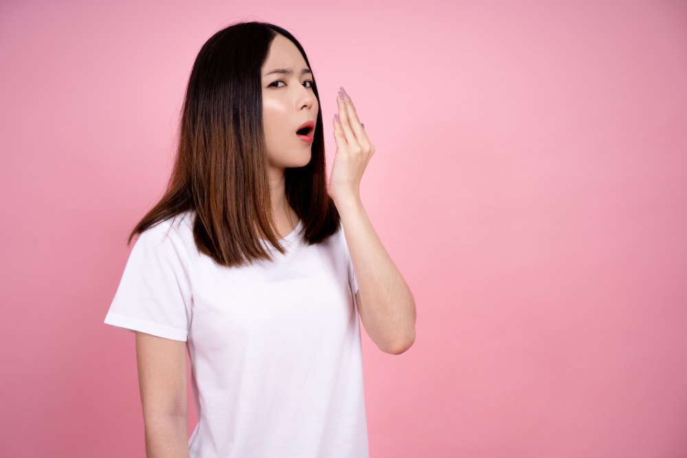 Portrait Photo of Woman in white t-shirt testing her bad breath