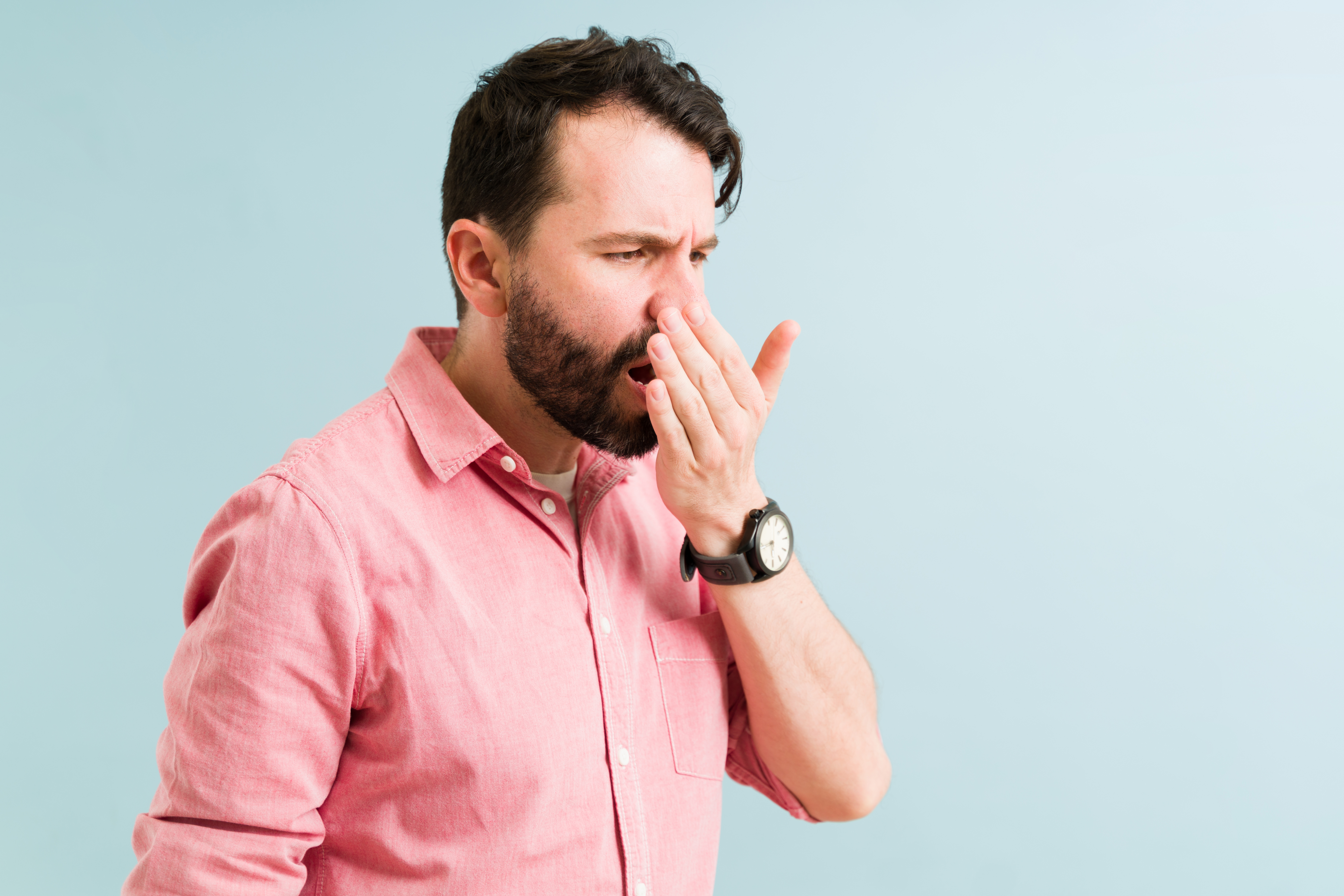 Portrait Photo of man in pink shirt holding his hand near his mouth